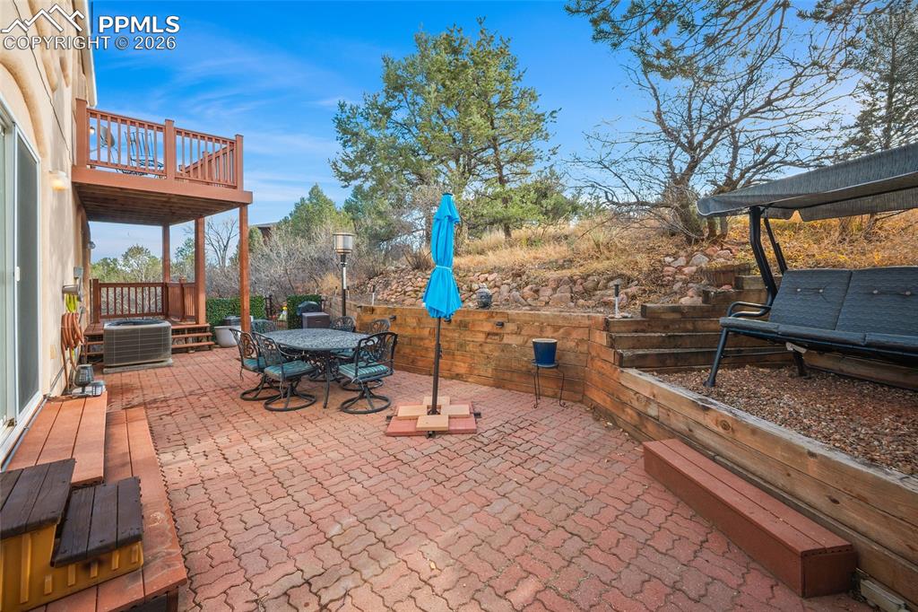 Southwest view of rear patio. Stone wall and brick patio. Rear top deck visible.