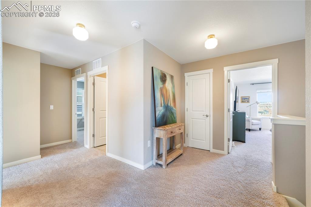 Upstairs view to primary and secondary bedrooms and laundry area