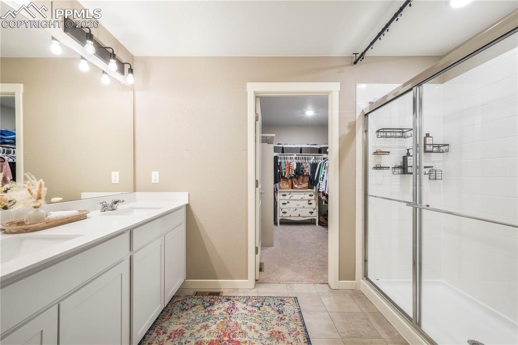 Primary bath with dual vanities, quartz counters, large walk in shower, separate water closet, linen closet and large walk in closet