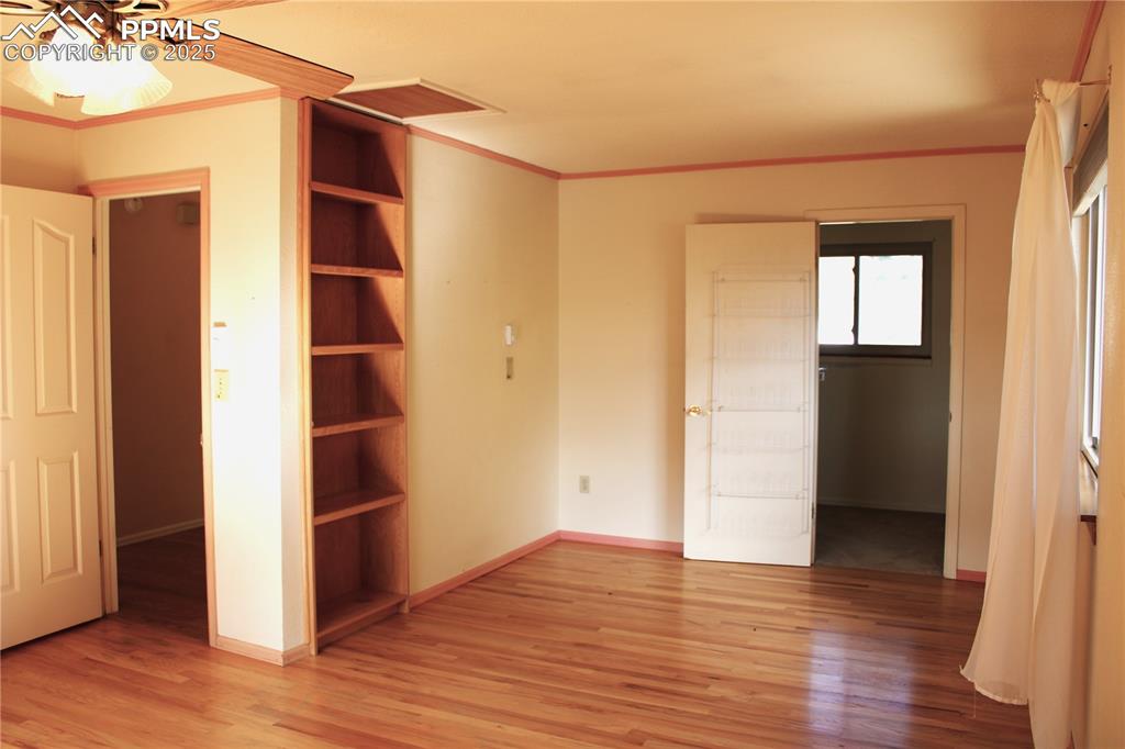 Primary bedroom featuring hardwood floors, built-ins, walk-in closet.