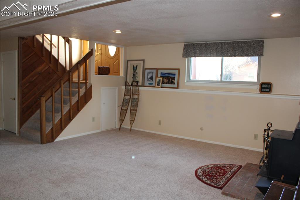 Family room with a wood stove, carpet, stairway, and recessed lighting