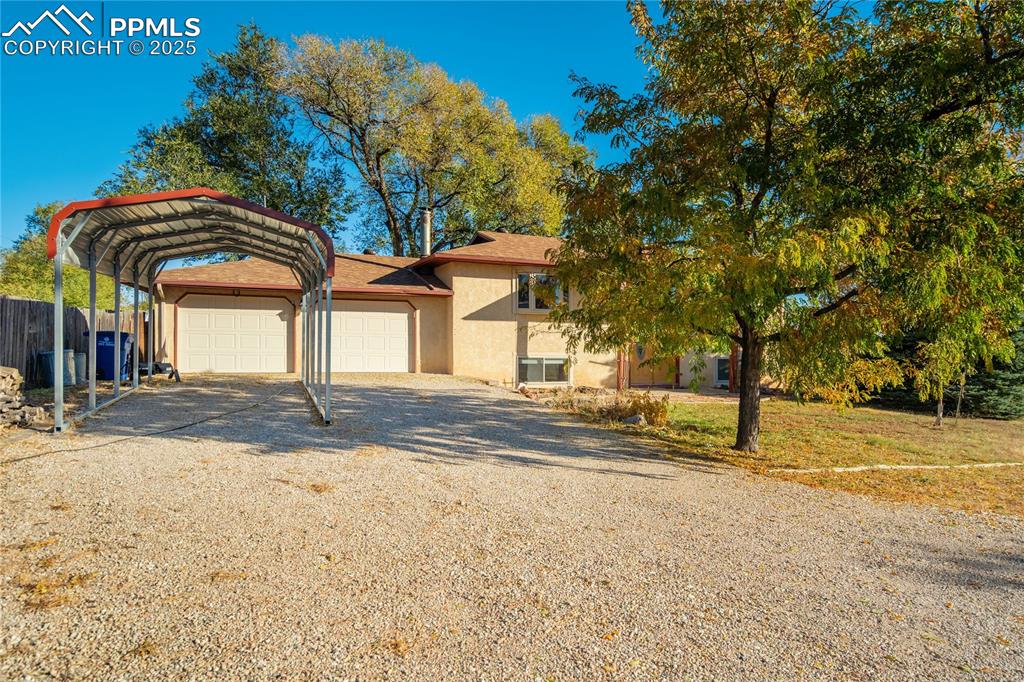 View of front of property with driveway, stucco siding, and a carport