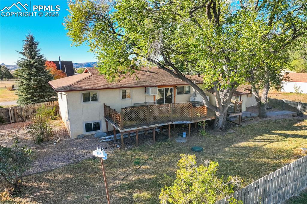 Back of house featuring a fenced backyard, a deck, stucco siding, and roof with shingles