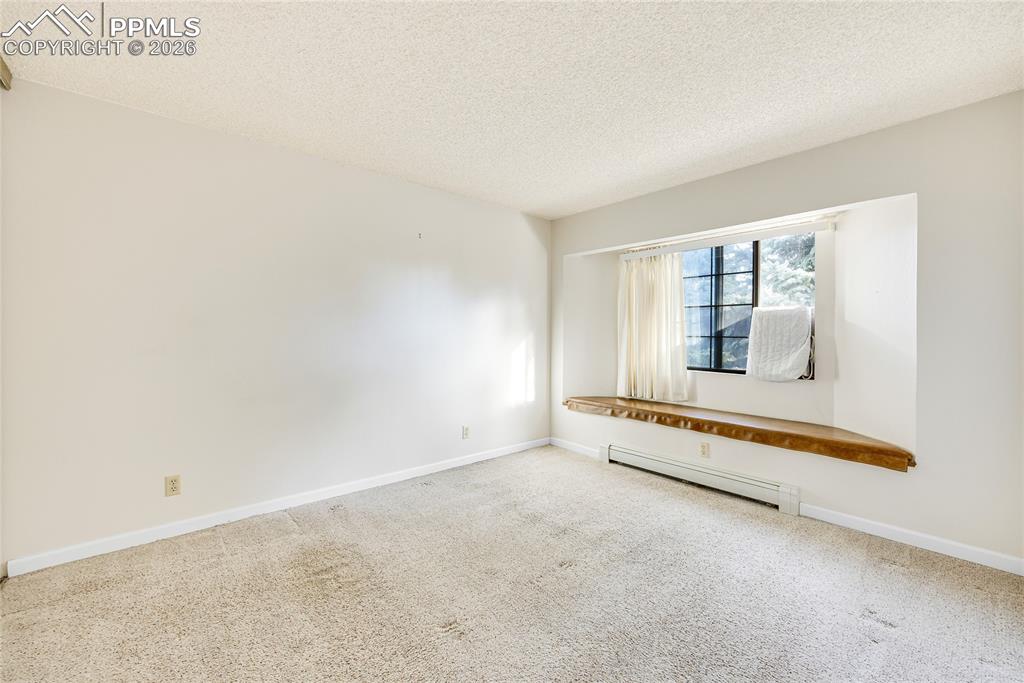 Carpeted spare room with a textured ceiling and baseboard heating