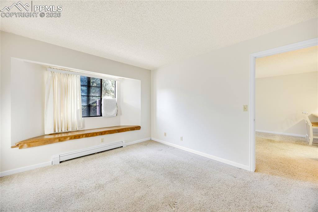 Unfurnished room with carpet floors, a baseboard radiator, and a textured ceiling