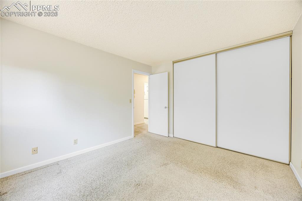 Unfurnished bedroom featuring a textured ceiling, carpet, and a closet