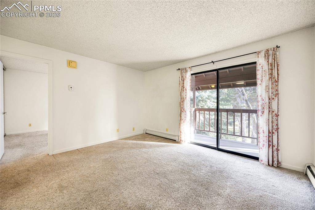 Spare room with carpet, a textured ceiling, and a baseboard radiator