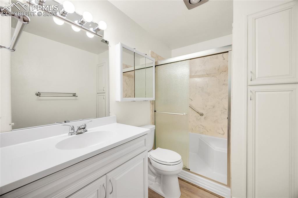 Full bath featuring vanity, a shower stall, and light wood-type flooring