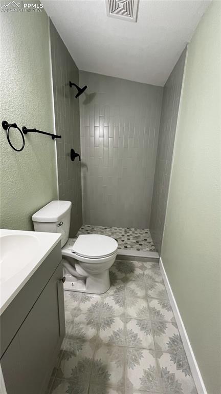 bathroom featuring a textured wall, a shower stall, and vanity