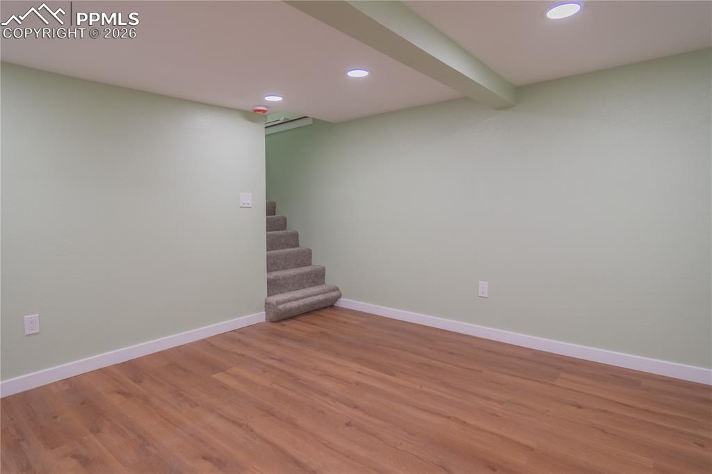 Finished below grade area featuring recessed lighting, wood finished floors, and stairs