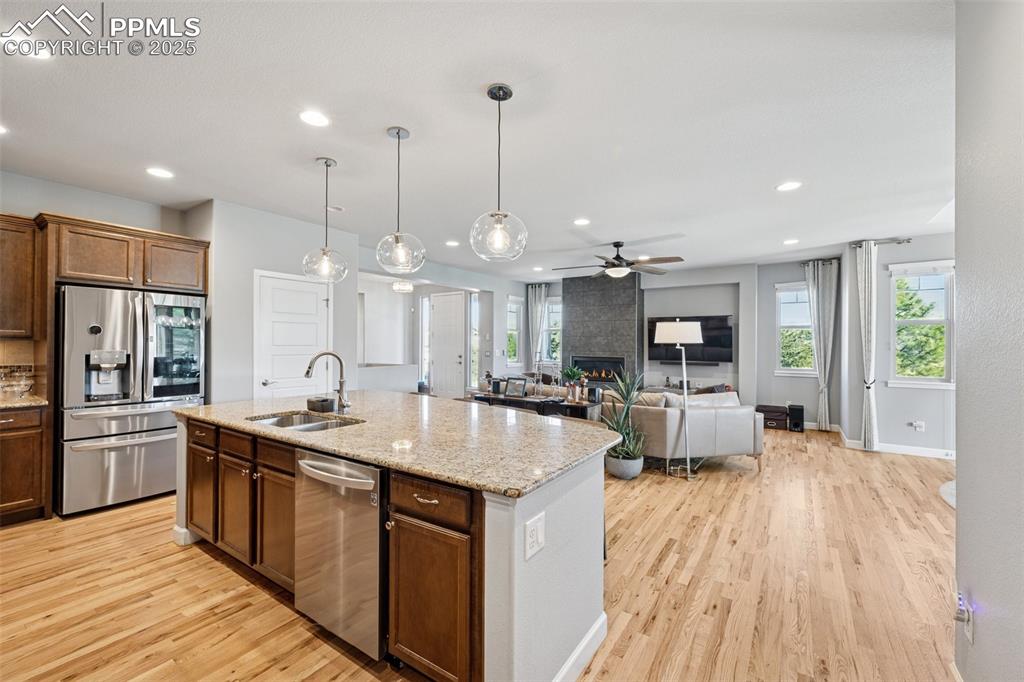Kitchen featuring appliances with stainless steel finishes, light wood-type flooring, a ceiling fan, an island with sink, and recessed lighting