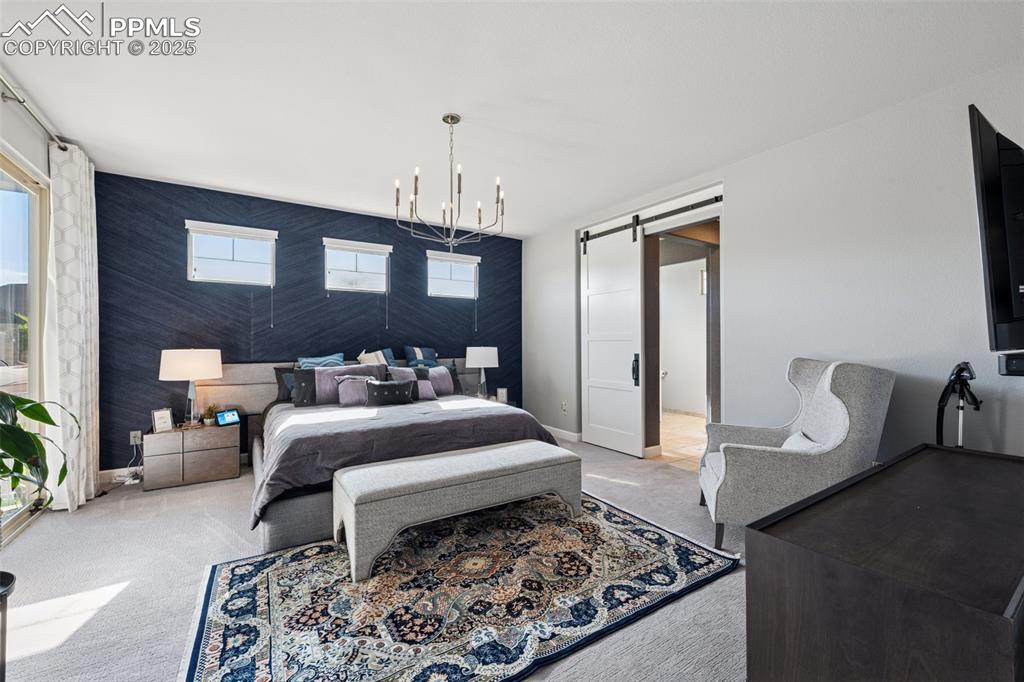 Carpeted bedroom featuring a barn door and a chandelier