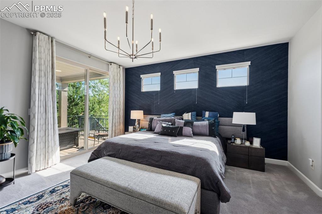 Carpeted bedroom featuring access to exterior, a chandelier, and multiple windows