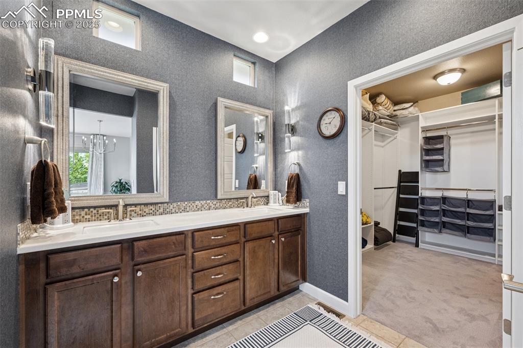 Full bathroom with double vanity, a walk in closet, tile patterned floors, healthy amount of natural light, and a textured wall