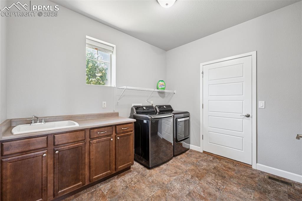 Laundry room featuring washing machine and dryer, stone finish floors, and cabinet space