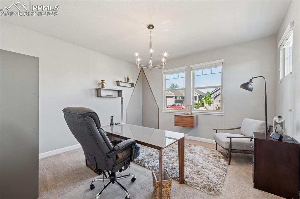 Office area featuring a chandelier, light colored carpet, and healthy amount of natural light