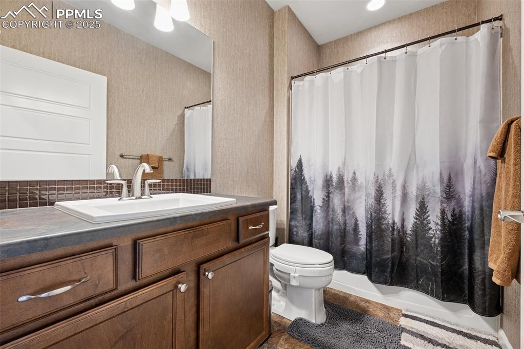 Full bath featuring vanity, decorative backsplash, and a shower with curtain