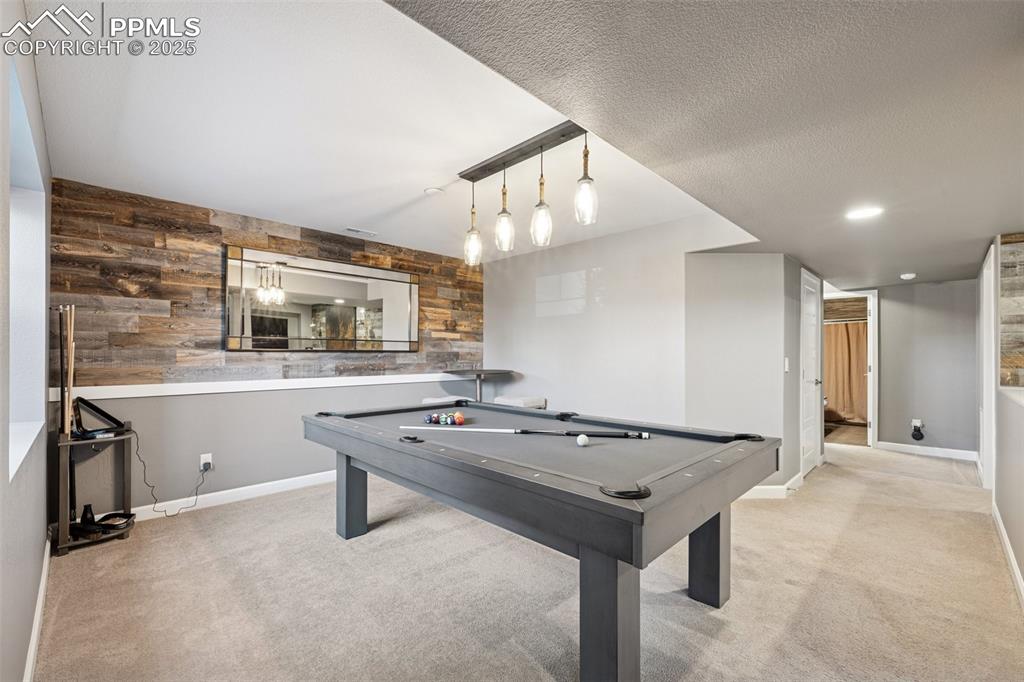 Playroom featuring carpet flooring, wooden walls, and pool table