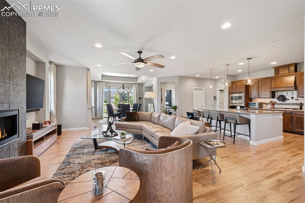 Living area featuring light wood-style floors, recessed lighting, a ceiling fan, and a tiled fireplace