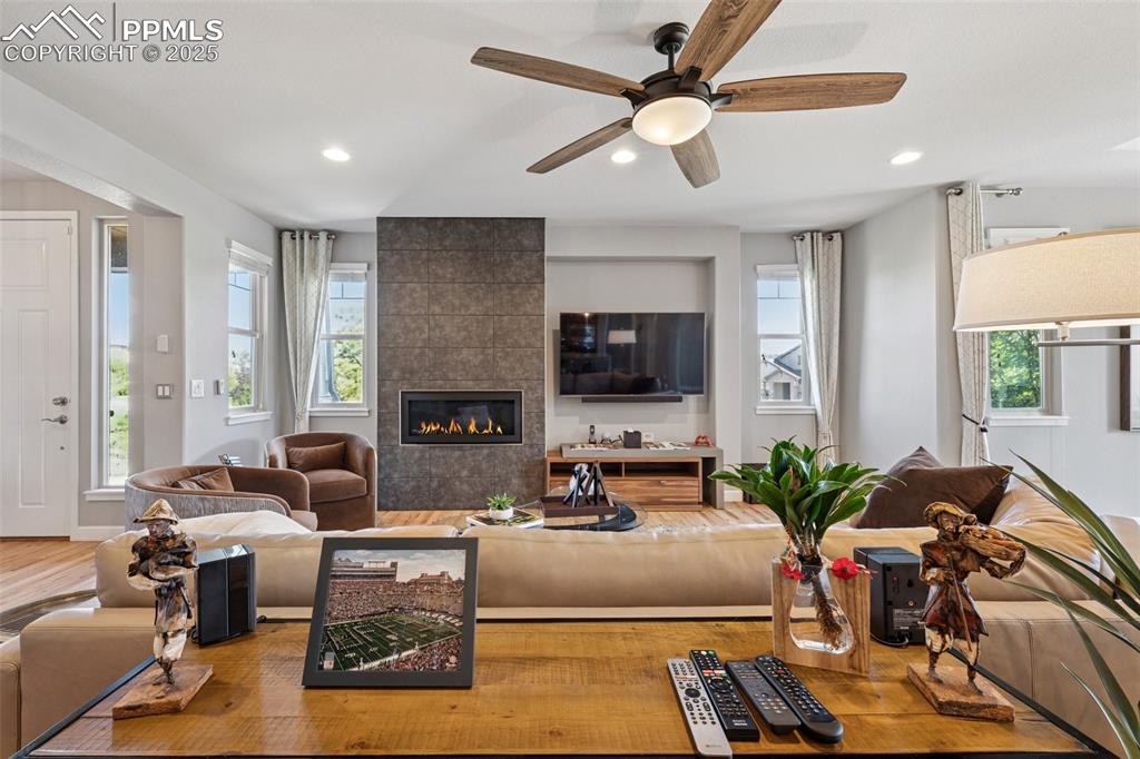Living room featuring wood finished floors, recessed lighting, ceiling fan, and a tiled fireplace