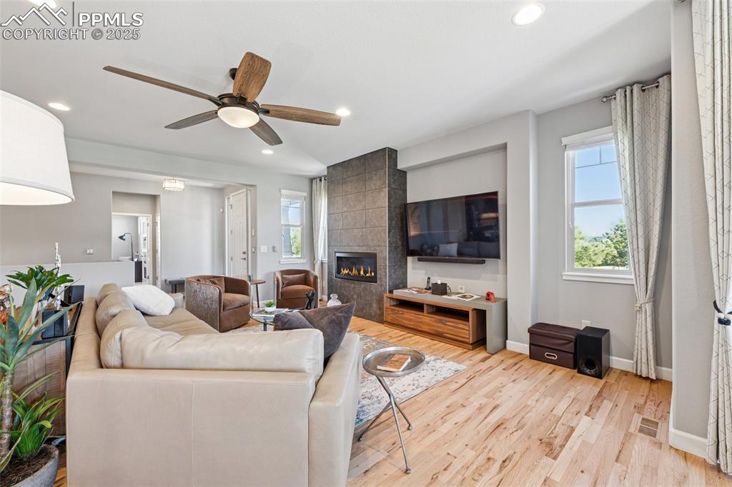 Living area featuring wood finished floors, recessed lighting, a fireplace, and ceiling fan