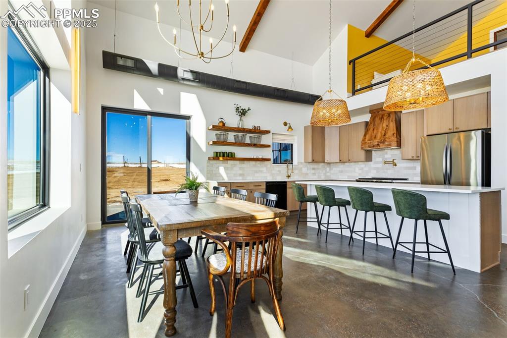 Dining area featuring high vaulted ceiling, a chandelier, beam ceiling, and finished concrete flooring