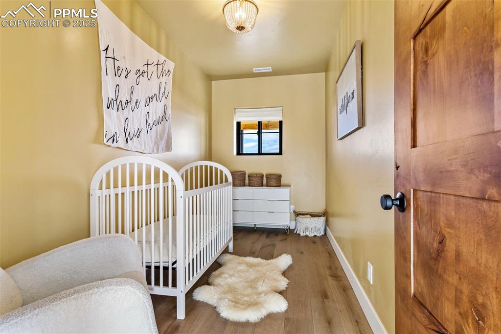 Bedroom with wood finished floors and a nursery area