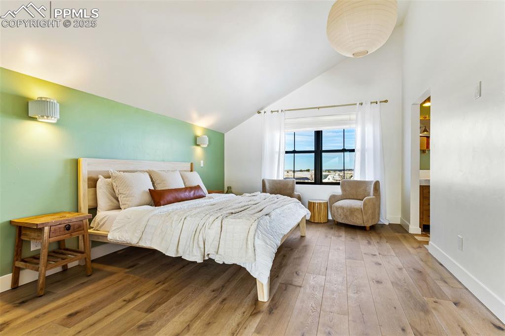 Bedroom with light wood-type flooring and high vaulted ceiling