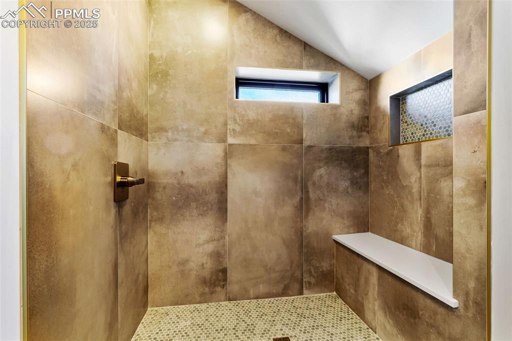 Bathroom featuring vaulted ceiling and a tile shower