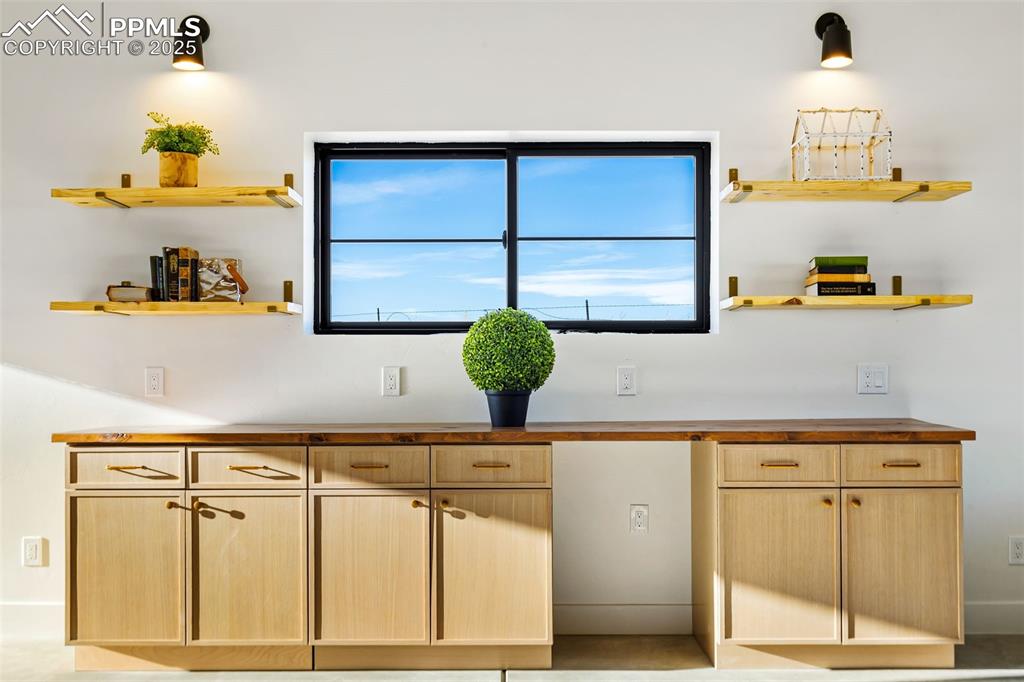 Kitchen with open shelves, light brown cabinetry, and wood counters