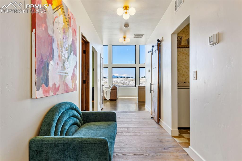Hallway with a barn door, light wood-type flooring, and washer / clothes dryer