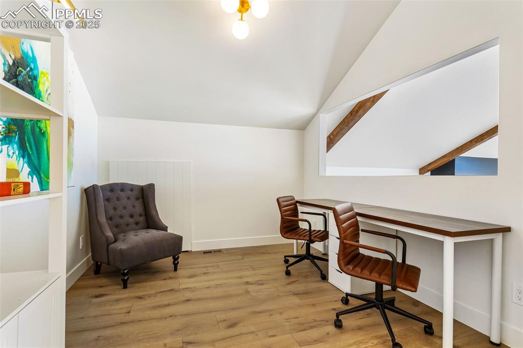 Office space with light wood-style flooring and vaulted ceiling