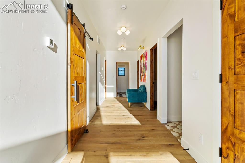 Corridor featuring a barn door and light wood-style floors