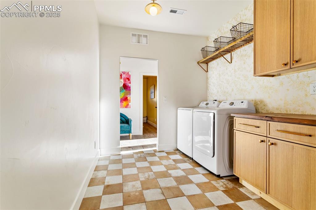 Laundry area with cabinet space, washing machine and dryer, and light floors