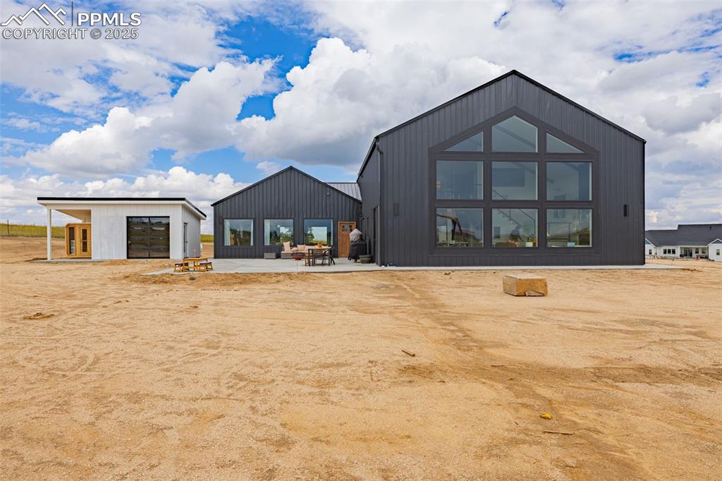 Back of property with a patio, a garage, and an outdoor structure