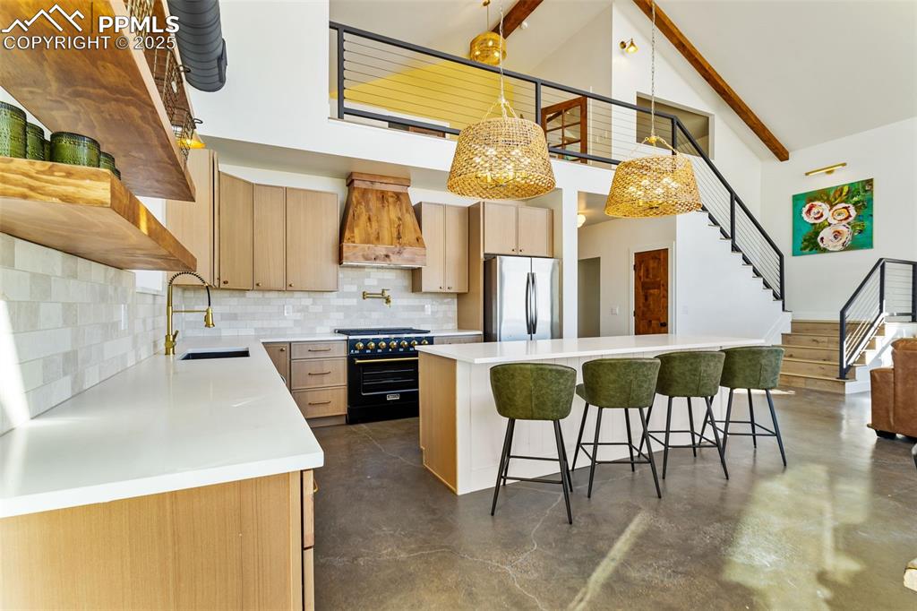 Kitchen featuring high vaulted ceiling, tasteful backsplash, high end stove, beamed ceiling, and a kitchen island