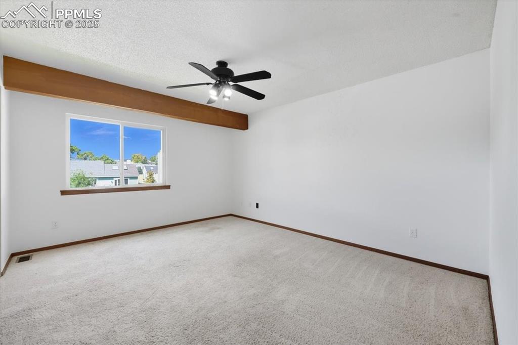 Carpeted empty room featuring a textured ceiling and a ceiling fan