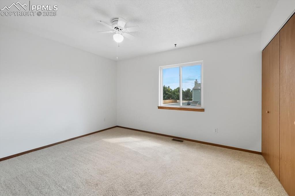 Unfurnished bedroom with a closet, carpet floors, ceiling fan, and a textured ceiling
