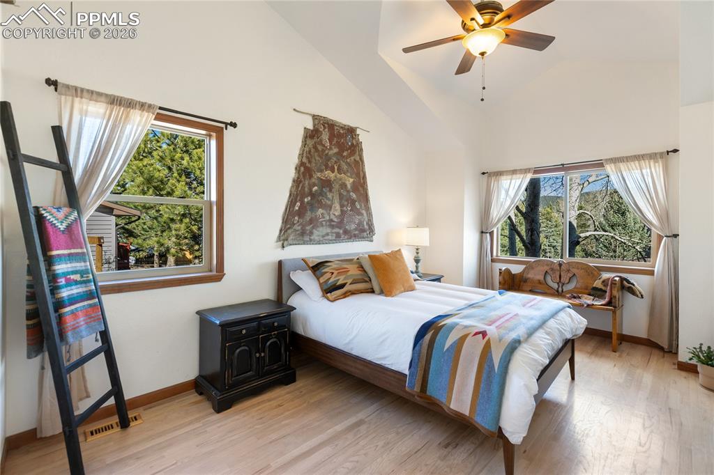 Primary bedroom is lacking nothing with vaulted ceilings, large windows, wood floors, mountain breeze and light fill the room