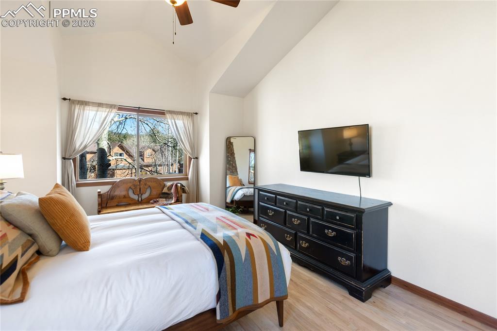 Primary bedroom is lacking nothing with vaulted ceilings, large windows, wood floors, mountain breeze and light fill the room