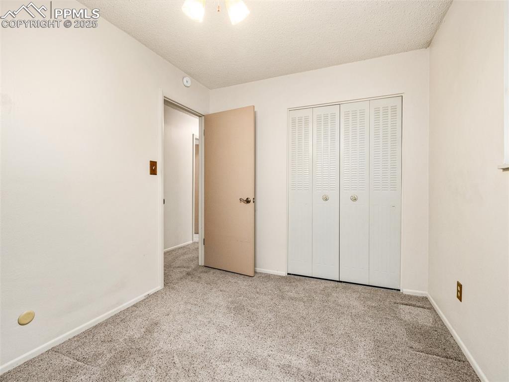 Unfurnished bedroom with carpet, a textured ceiling, and a closet