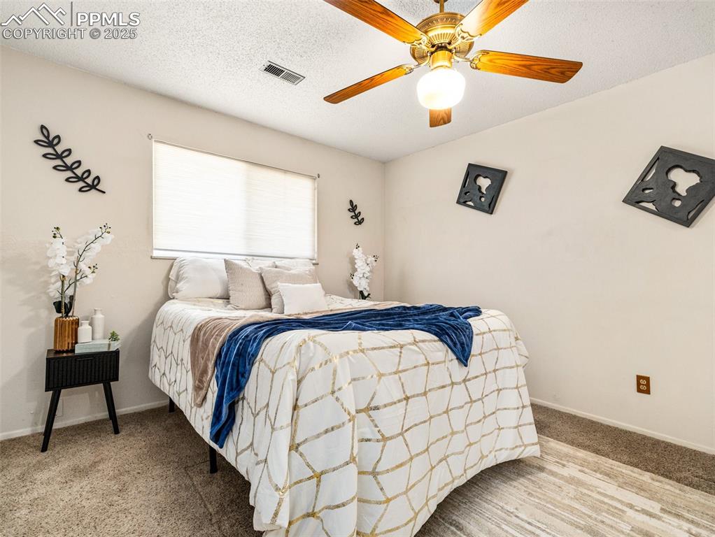 Bedroom featuring a textured ceiling, carpet floors, and a ceiling fan