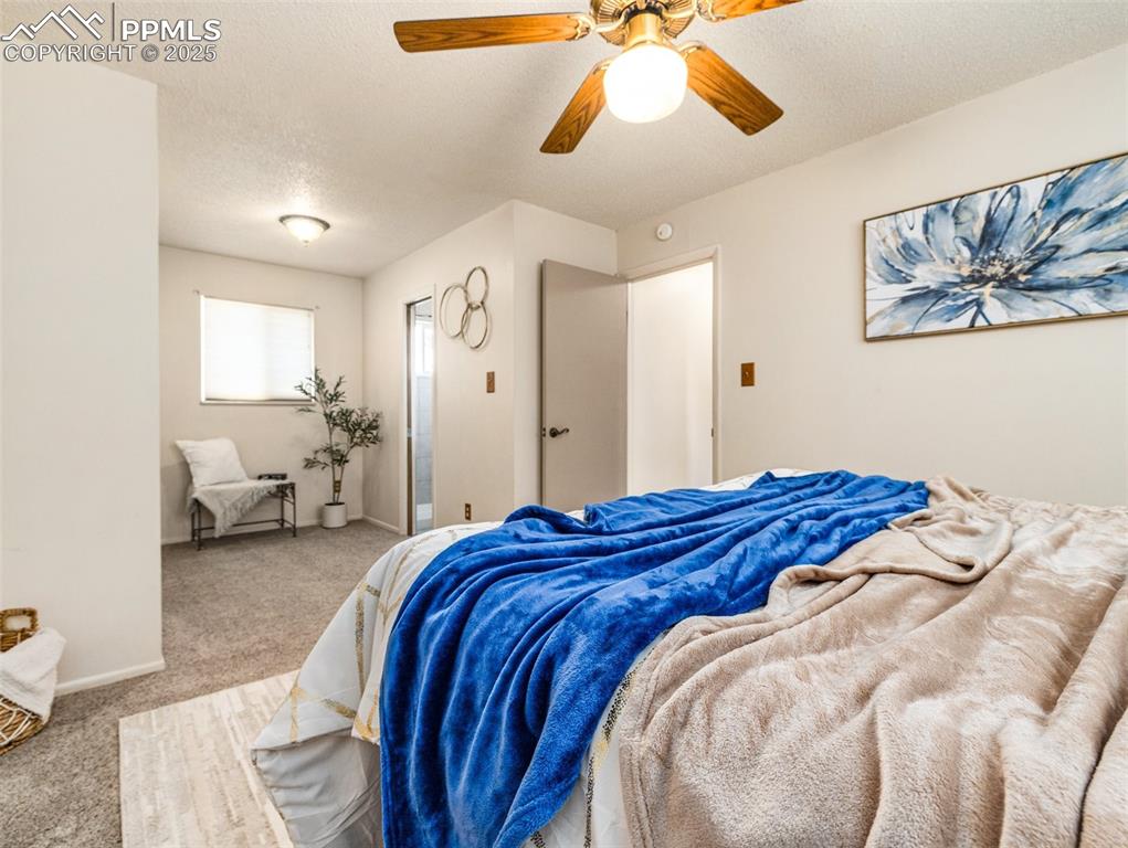 Carpeted bedroom with a textured ceiling and ceiling fan