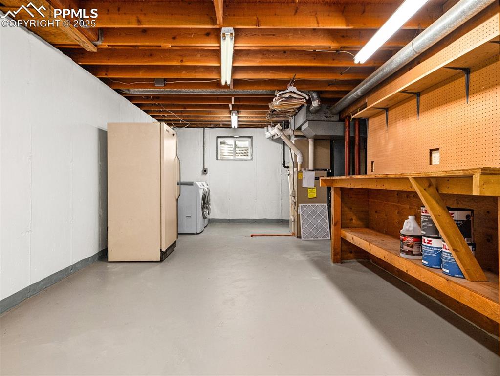 Basement with freestanding refrigerator and heating unit,