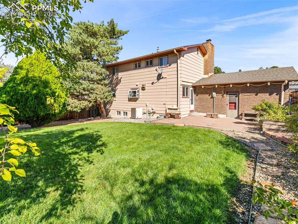 Back of house with a patio, a chimney, and brick siding