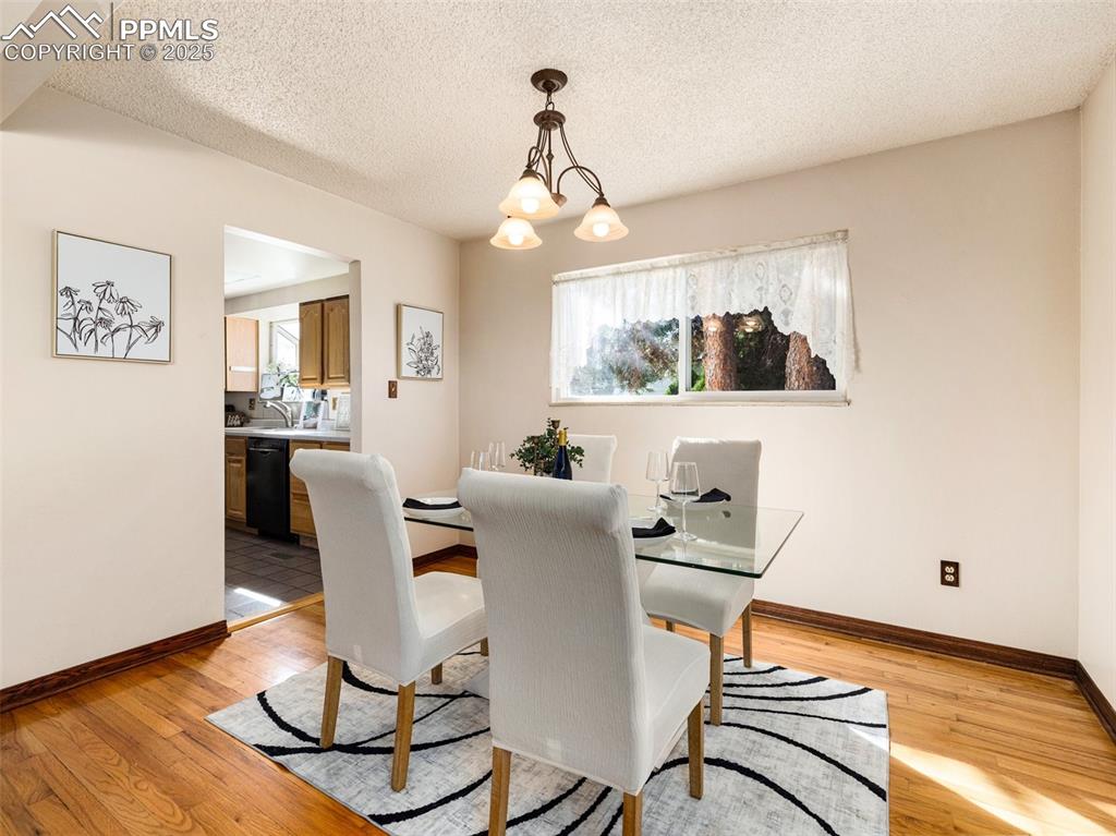 Dining area featuring plenty of natural light, a textured ceiling, light wood-type flooring, and a chandelier