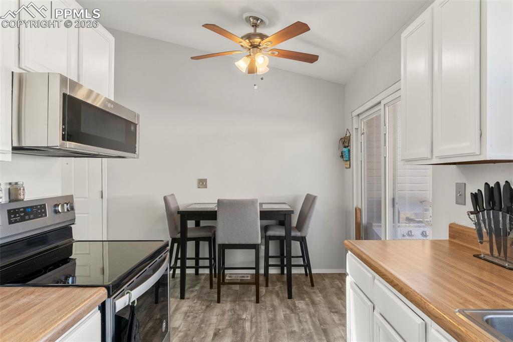 Kitchen featuring stainless steel appliances, white cabinets, light countertops, and vaulted ceiling