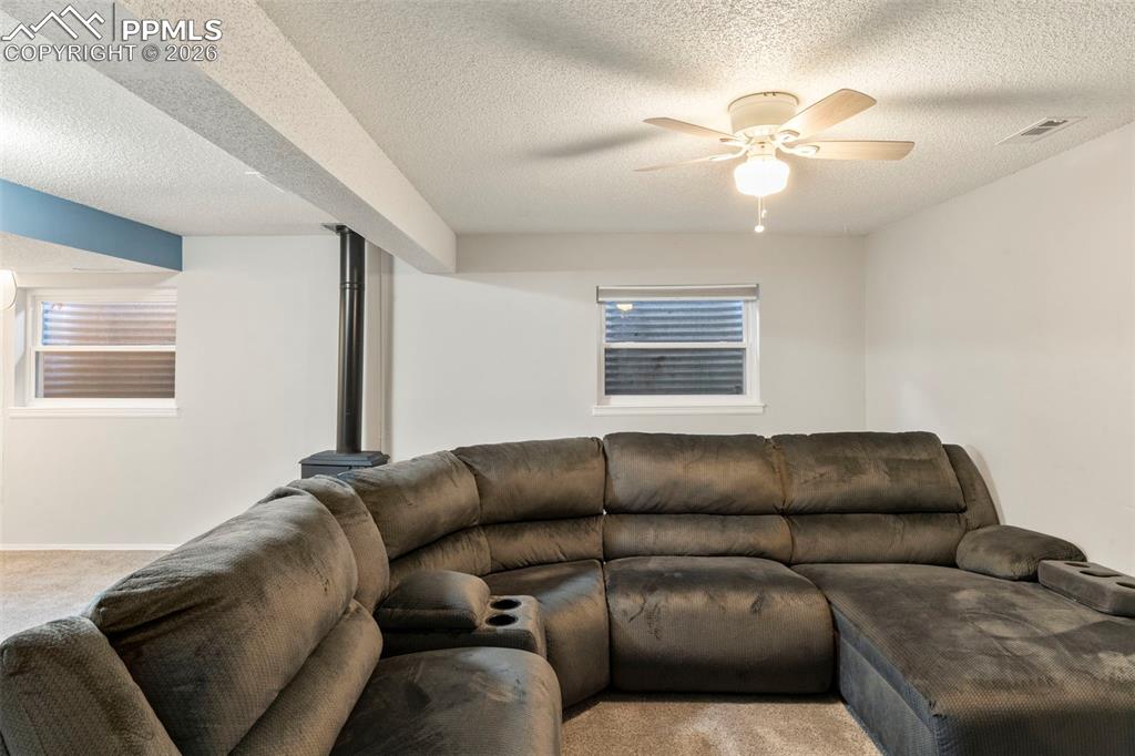 Living area featuring light carpet, a textured ceiling, and ceiling fan