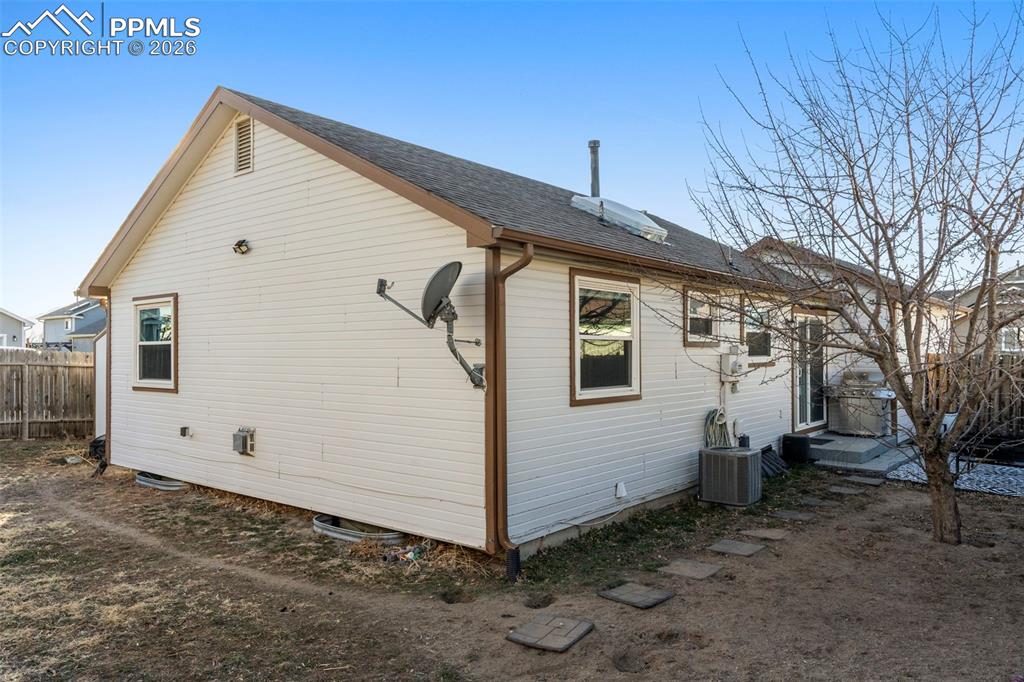 View of side of property featuring a central AC unit and a shingled roof