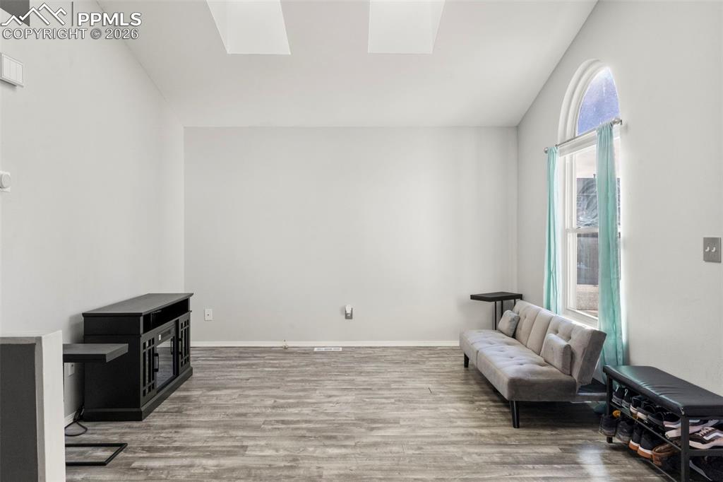 Sitting room featuring a skylight, lofted ceiling, and light wood-style floors